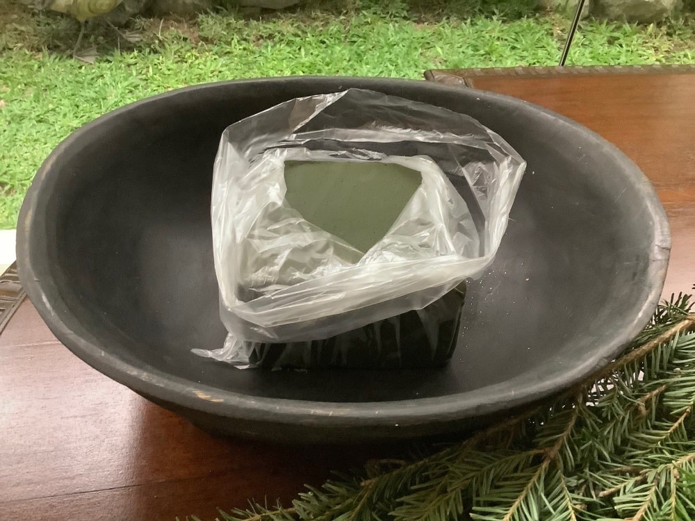 Water-soaked floral foam wrapped in plastic and placed in a bowl. Water-soaked floral foam wrapped in plastic and placed in a bowl.